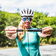 Load image into Gallery viewer, Person in cycling gear holding a Lezyne Presta Pocket Drive Mini Pump with a blurred green outdoor background