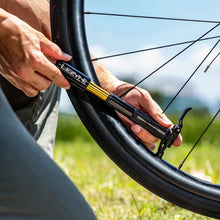 Load image into Gallery viewer, Person inflating a bicycle tire with a Lezyne Presta Pocket Drive Mini Pump in an outdoor setting.